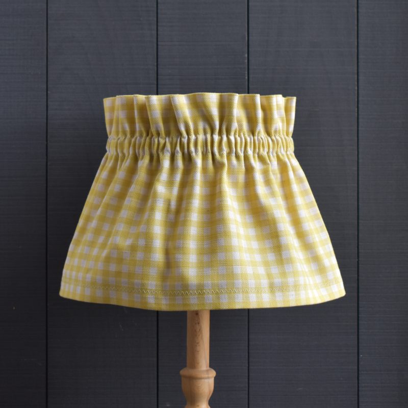 This is Dolly our Dolly Yellow Gingham Scrunchie Lampshade This a two piece set, the cover and the lampshade underneath. The cover slips on top easily, gathers beautifully and can be removed for hand washing. It is slightly bigger than the lampshade underneath. It is designed to be prouder at the top and longer at the base.